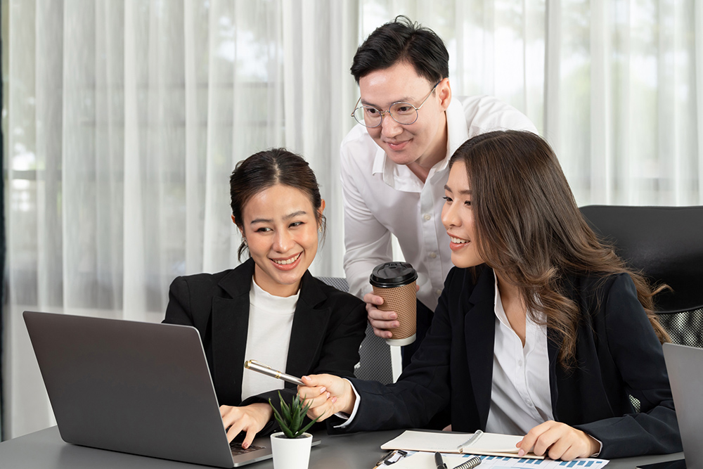 Harmony in office concept as business people analyzing dashboard paper together in workplace. Young colleagues give ideas at manager desk for discussion or strategy planning about project.